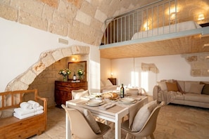 A dining area with a stone archway, wooden furniture, and a balcony. - ALL Casa Tino – 3 Bedrooms & 2 Modern Bathrooms (Polignano a Mare)
