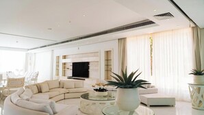Una sala de estar moderna con un sofá seccional, una mesa de centro de vidrio y un televisor de pantalla plana montado en la pared.