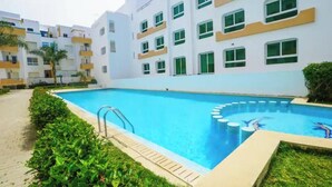 A swimming pool surrounded by a building with multiple floors and balconies. - Cozy 2-bedroom apartment in beautiful Tangier Achakar Hill (Tangier)