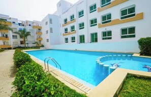 A swimming pool surrounded by a building with multiple floors and balconies. - Cozy 2-bedroom apartment in beautiful Tangier Achakar Hill (Tangier)