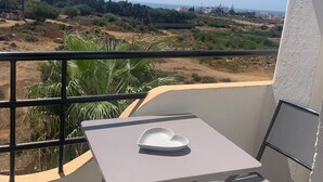 A balcony with a table and chairs, overlooking a landscape with greenery and buildings. - Cozy 2-bedroom apartment in beautiful Tangier Achakar Hill (Tangier)