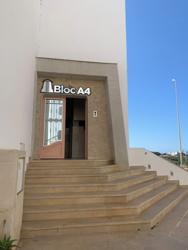 A building entrance with a sign reading 'Bloc A4' and a set of concrete stairs leading up to it.