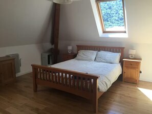 Ein Schlafzimmer mit einem hölzernen Bett, einem Nachttisch, einer Heizung und einem Oberlicht.
