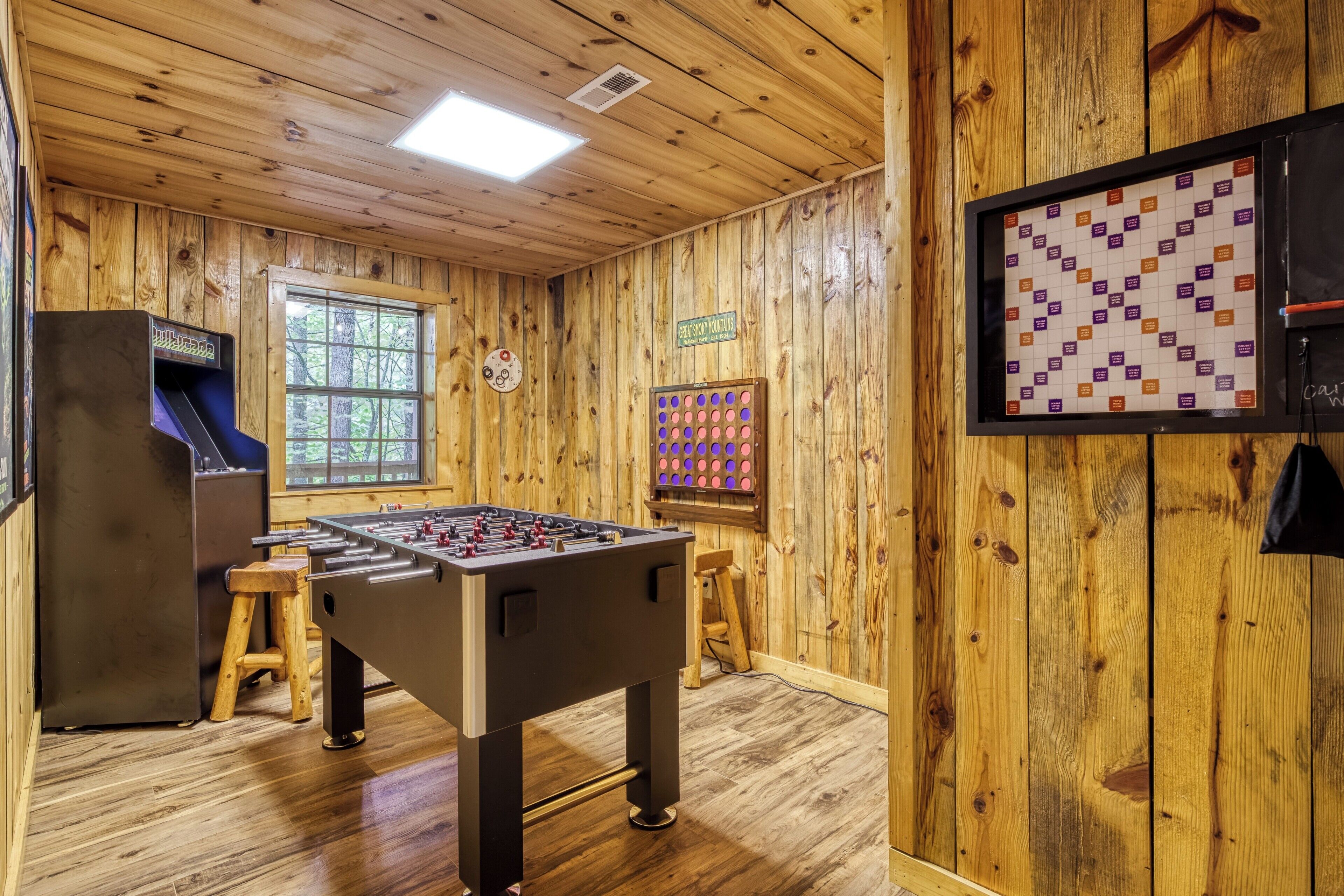Una habitación con paredes de madera, una mesa de fútbol de mesa, un dardo y una máquina tragamonedas.
