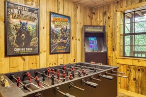 A room with wooden walls, a foosball table, and movie posters. - Our Peaceful Bearadise, Hot Tub, Game Room, Free Tickets (Sevierville)