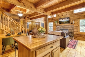A wooden cabin interior with a dining area, a fireplace, and a staircase. - Our Peaceful Bearadise, Hot Tub, Game Room, Free Tickets (Sevierville)