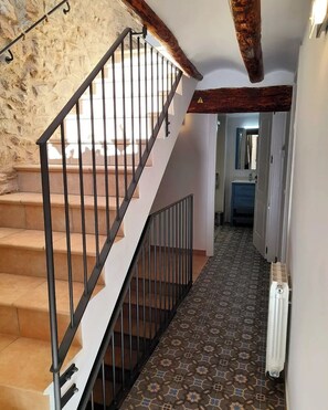 A staircase with metal railings leading to a room with a tiled floor and a radiator. - Cal Passió, a fully renovated historic home. Next to the Prades Mountains. (Vimbodí i Poblet)