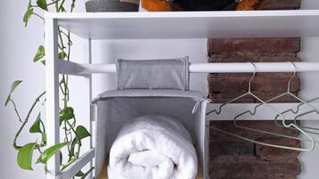 A white metal shelf with a teddy bear, a woven basket, and a potted plant.