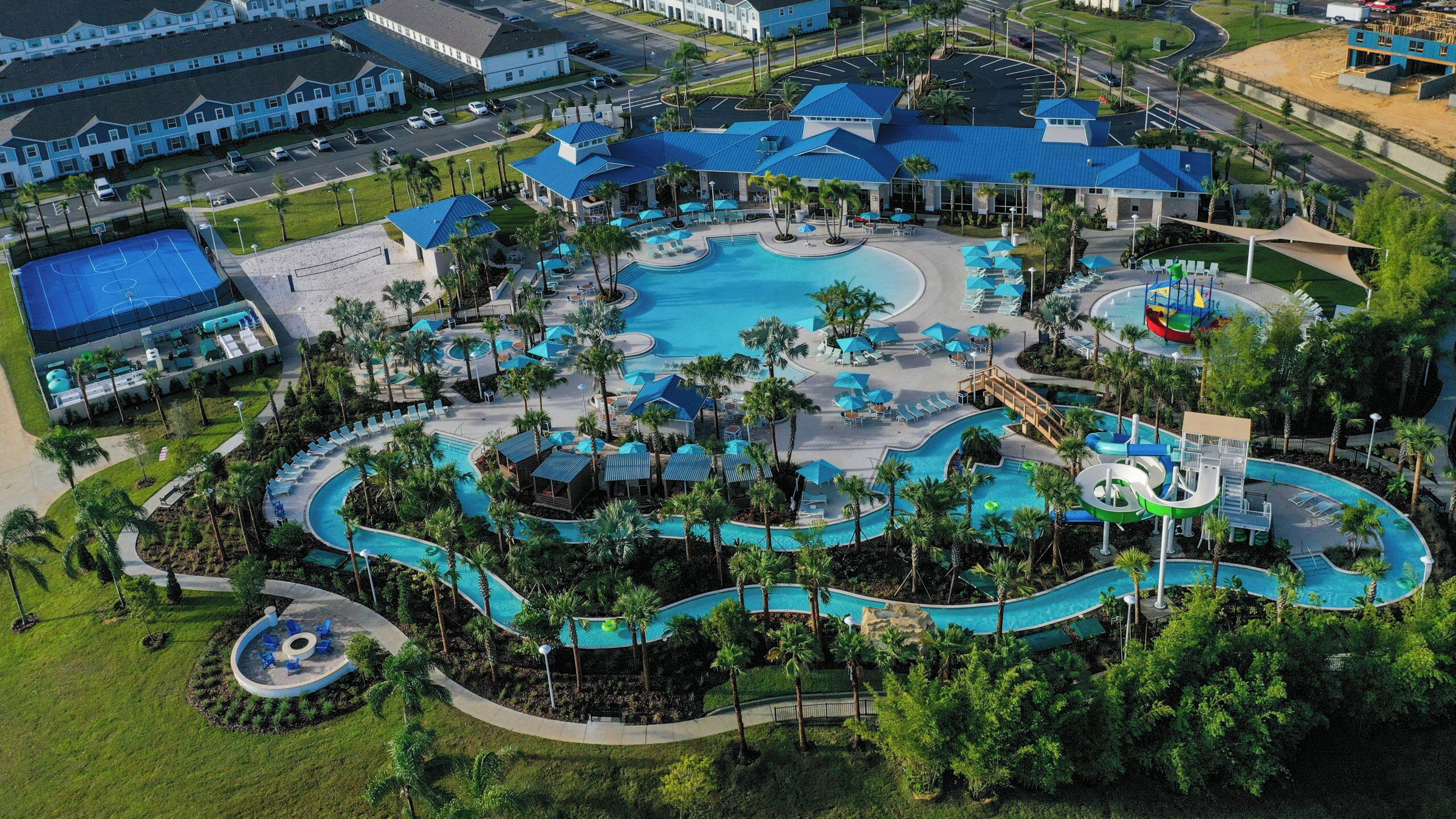An aerial view of a resort with multiple swimming pools, palm trees, and a large building complex.