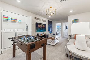 A room with a foosball table, a TV, and a sofa. - Magical 5BR Disney Getaway with Private Pool, Themed Rooms & Resort Amenities (Davenport)