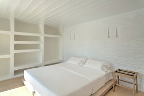 Ein minimalistisches Schlafzimmer mit einem großen Bett, integrierten Regalen und einem Nachttisch aus Holz.