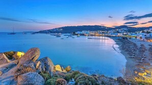 Uma vila costeira com uma praia, barcos e um cais.
