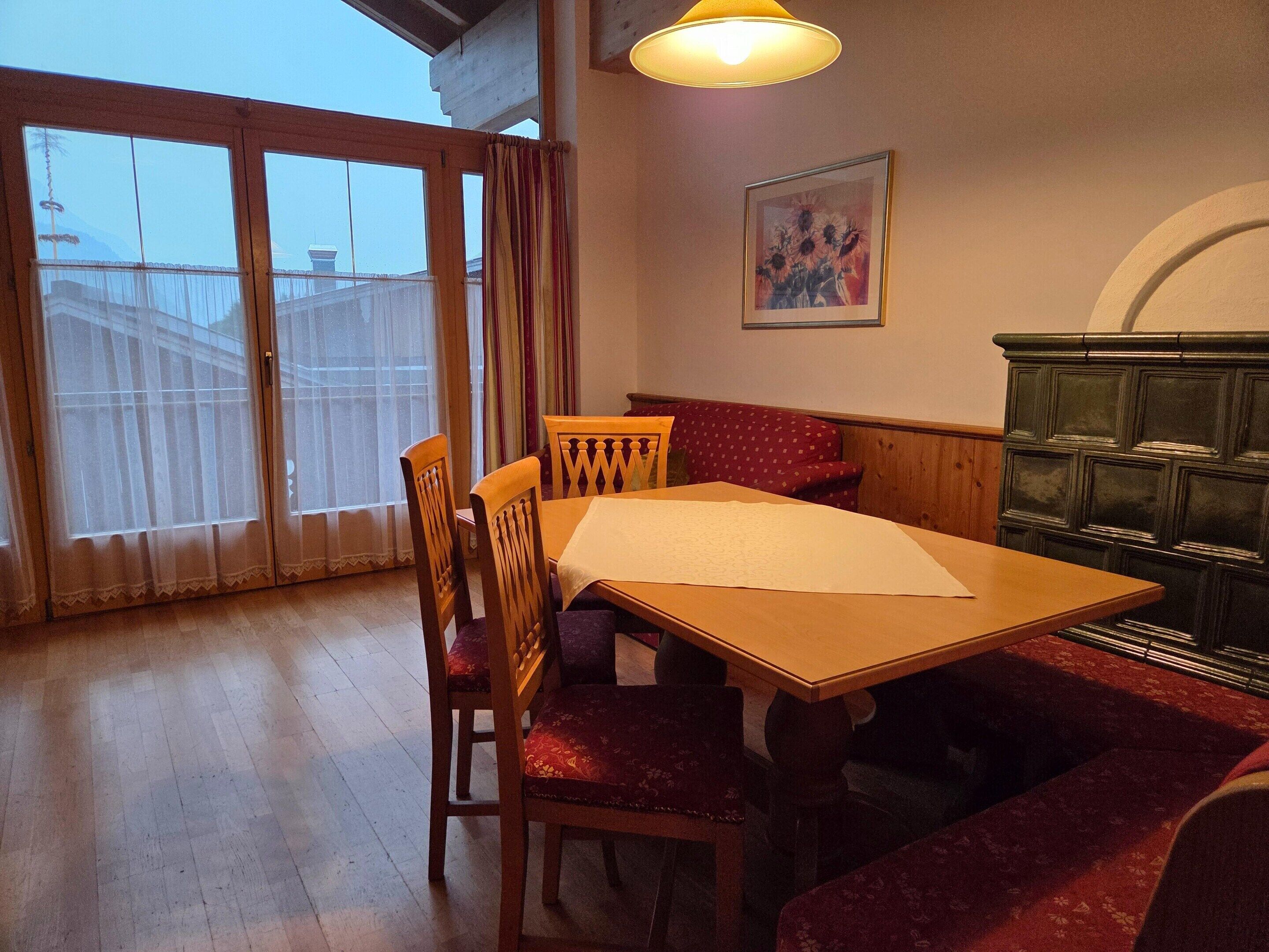 Ein Essbereich mit Holztisch und Stühlen, einer Bank, einem Schrank und einem Bild an der Wand.
