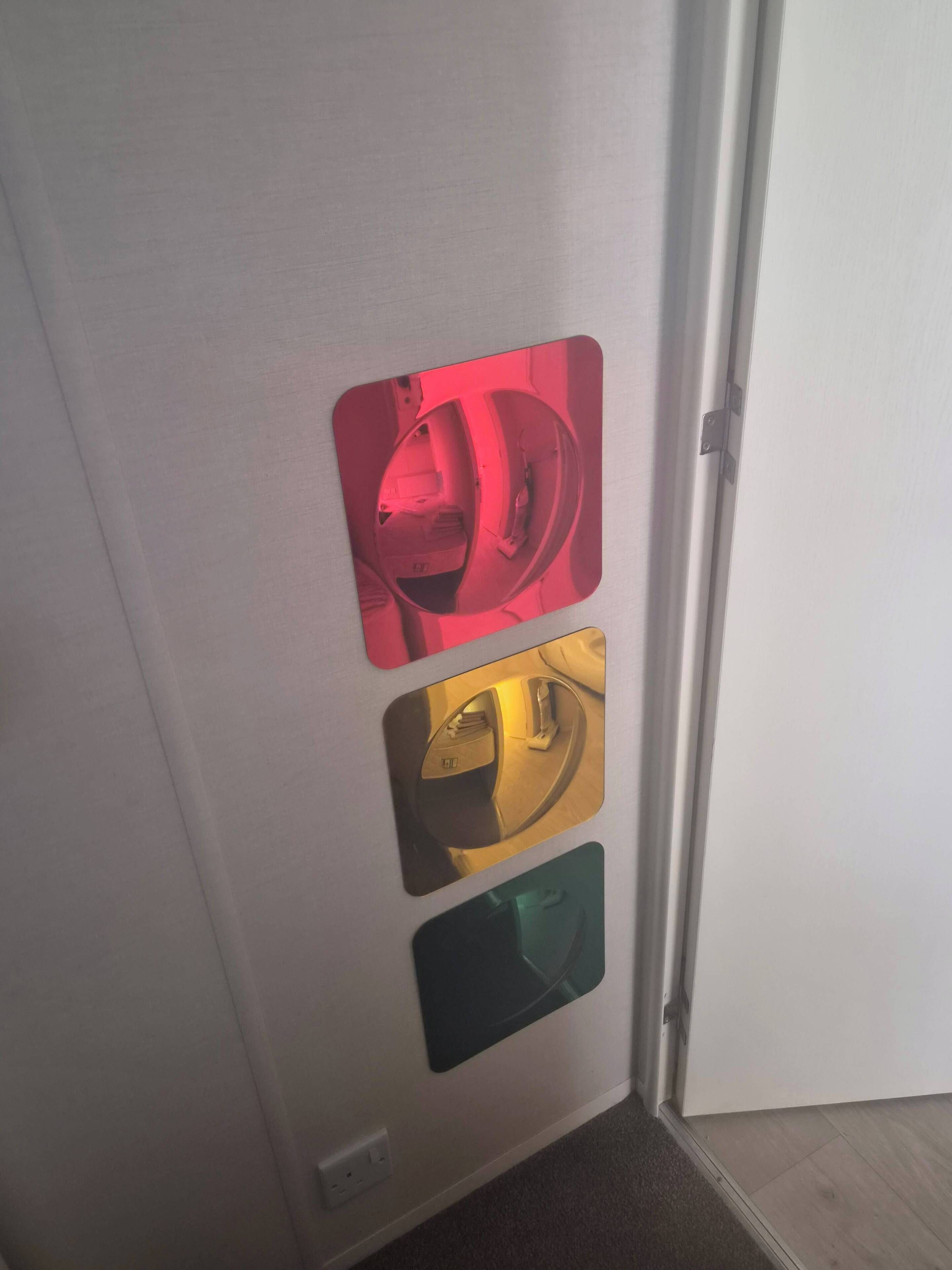 Una porta con tre pannelli riflettenti nei colori rosso, oro e verde.