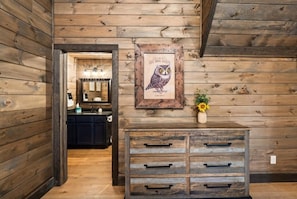 Ein Holzinterieur mit einem gerahmten Kunstwerk mit Eule, einer Kommode mit Schubladen und einem Küchenbereich im Hintergrund.