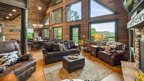 A spacious living room with a high ceiling, large windows, and a fireplace. - CoveMtnComf: Pool, MtnViews, HotTub, Wifi, Pets, Theater, Games (Sevierville)