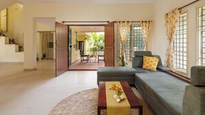 A living room with a sofa, a coffee table, and a view of the outside. - Villa Terracotta by Redolivenr Art of Living3bhk (Bengaluru)