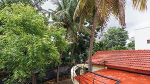 A residential area with a red-tiled roof, a brick pathway, and lush greenery including palm trees. - Villa Terracotta by Redolivenr Art of Living3bhk (Bengaluru)