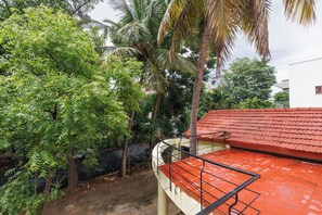 A residential area with a red-tiled roof, a brick pathway, and lush greenery including palm trees. - Villa Terracotta by Redolivenr Art of Living3bhk (Bengaluru)