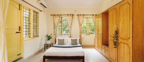 A bedroom with a bed, curtains, a ceiling fan, and a large wardrobe.