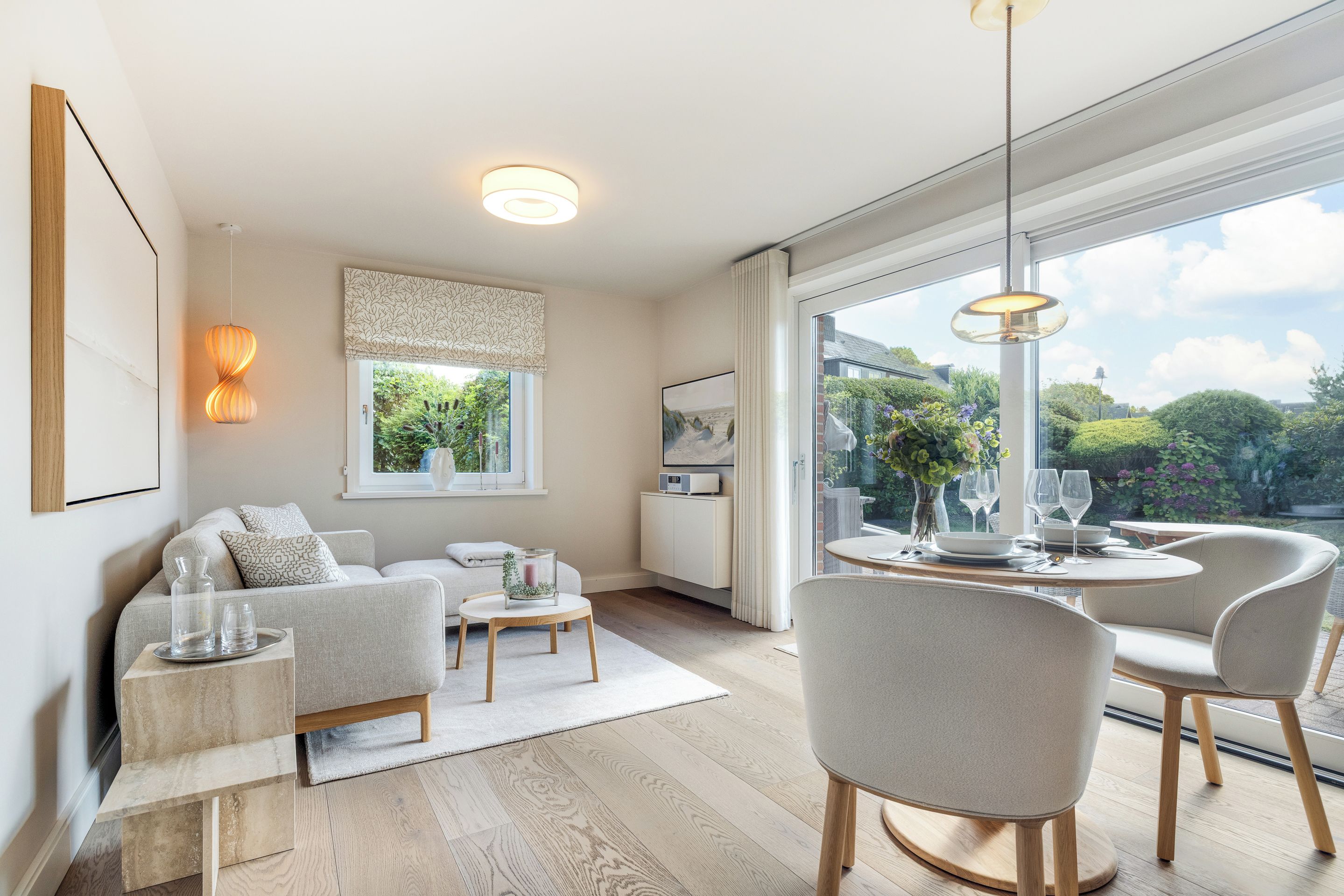 A modern living room with a sofa, coffee table, and dining area with chairs and a table.