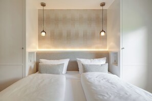 A double bed with two pillows, a headboard, and pendant lights. - Your modern retreat in Wenningstedt. (Wenningstedt-Braderup (Sylt))