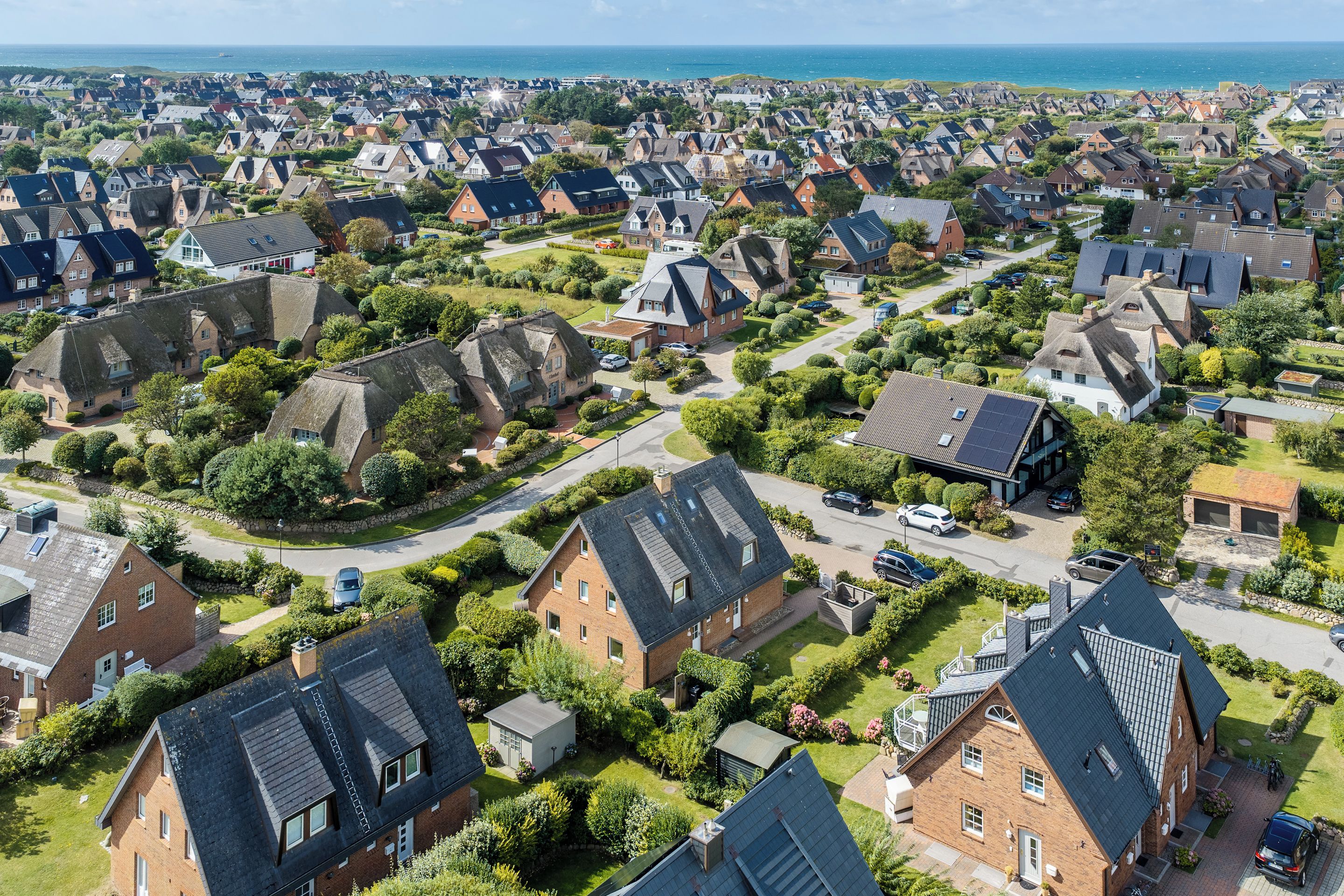 Un quartier résidentiel avec des maisons, des rues et une vue sur la mer.