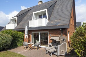 A two-story house with a balcony, a patio with outdoor furniture, and a brick exterior. - Your modern retreat in Wenningstedt. (Wenningstedt-Braderup (Sylt))