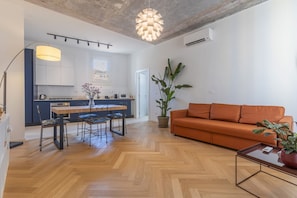 A modern living space with a dining area, a sofa, and a large potted plant. - A modern 120 sqm apt located on the third floor of a period building, it is equipped with every comfort to comfortably host two adults and a child.The apartment is located in a centrally located area (ZTL in Italian), less than 160 mt from Torresotto di  (Bologna)