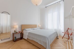 A bedroom with a wooden bed, bedside tables, a mirror, and a hanging light fixture. - A modern 120 sqm apt located on the third floor of a period building, it is equipped with every comfort to comfortably host two adults and a child.The apartment is located in a centrally located area (ZTL in Italian), less than 160 mt from Torresotto di  (Bologna)