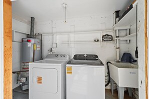 Een wasserette met een wasmachine, droger en een bord dat aangeeft dat dit de wasserette is.