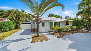 Ein Wohnhaus mit Auffahrt, einer Palme und umgebender Bepflanzung.