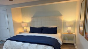 Ein Schlafzimmer mit einem Bett, Nachttischlampen, einem Nachttisch und einem gerahmten Bild an der Wand.
