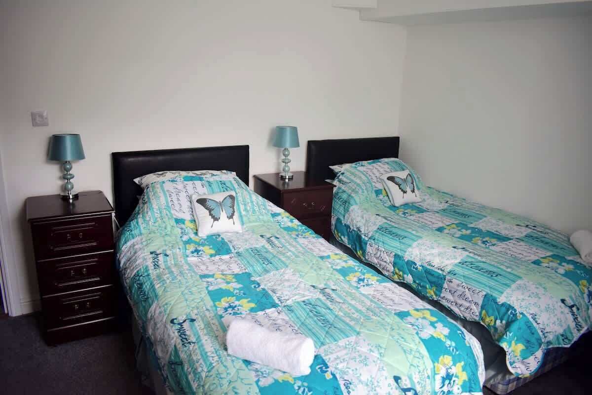 Ein Hotelzimmer mit zwei Einzelbetten, jeweils mit passender Kopfteil und Nachttisch.