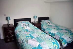 Hotellihuone, jossa on kaksi erillistä sänkyä, ja molemmissa on samanlaiset päätylevyt ja yöpöydät.