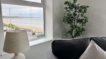 Una habitación con ventana que da a una playa, una lámpara y una planta.