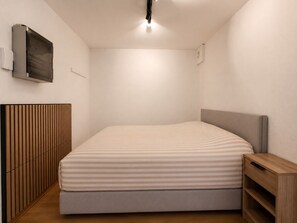 A bedroom with a bed, a wooden headboard, a bedside table, and a wall-mounted television. - Seafront Apartment in Middelkerke (Middelkerke)