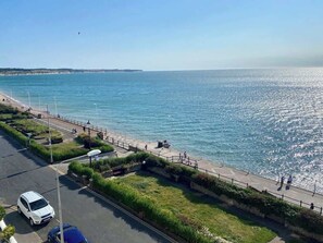 Un paseo marítimo con sendero adoquinado, zonas verdes y vista despejada al mar.