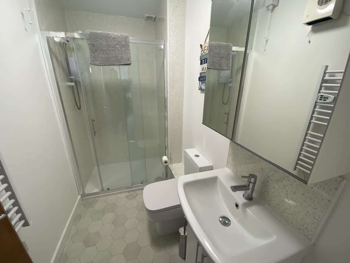 A bathroom with a glass-enclosed shower, a white sink, and a toilet.