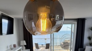 Uma sala de estar moderna com área de jantar, uma janela ampla com vista e um candeeiro esférico singular.