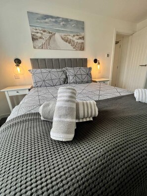 Ein Schlafzimmer mit einem Bett, zwei Nachttischen, einer Wandlampe und einem Bild.