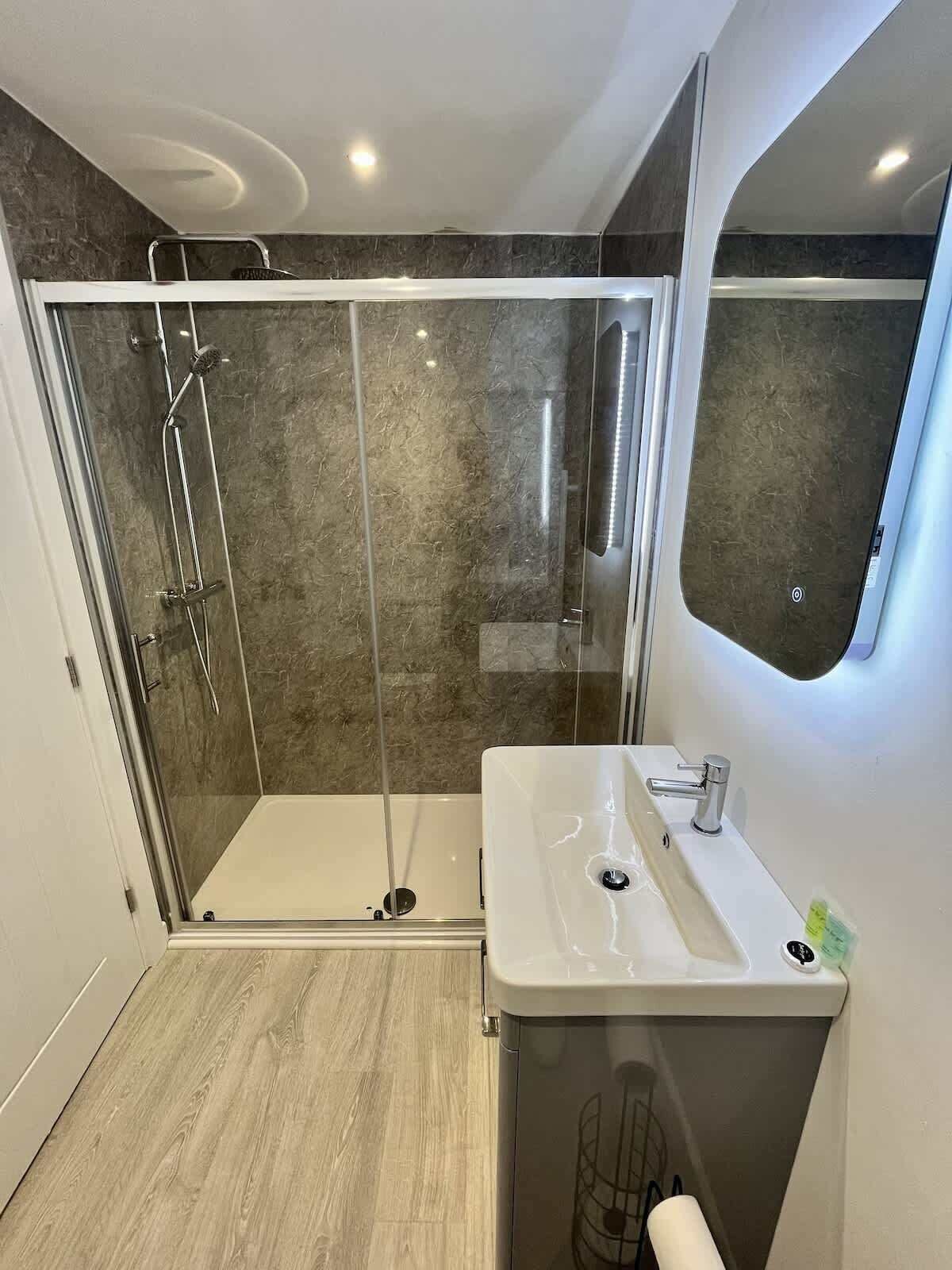 Un bagno moderno con doccia vetrata, lavandino bianco e specchio.
