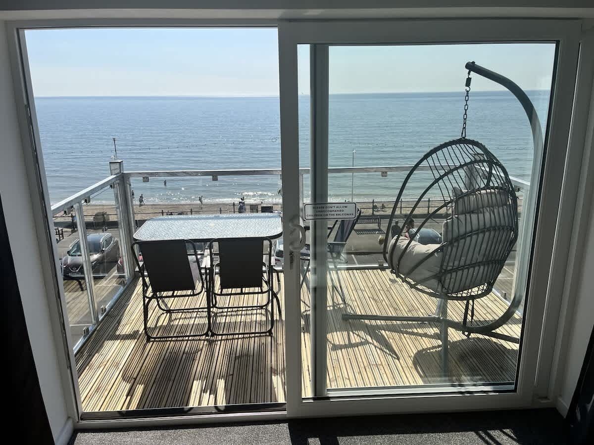 Un balcón con mesa y sillas, vistas al mar.