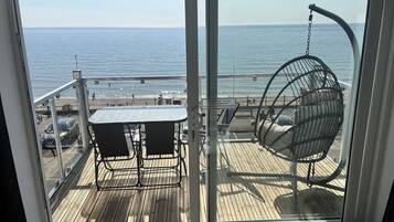 Un balcón con mesa y sillas, vistas al mar.