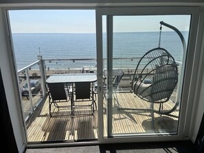 Un balcón con mesa y sillas, vistas al mar.