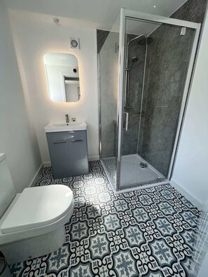 Ein Badezimmer mit Toilette, Waschbecken und Duschbereich.