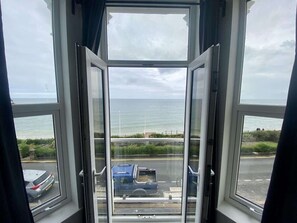 Blick aus einem Fenster auf das Meer und einen Parkplatz.