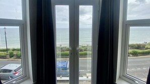 Vista a través de una ventana que muestra el mar y una carretera.