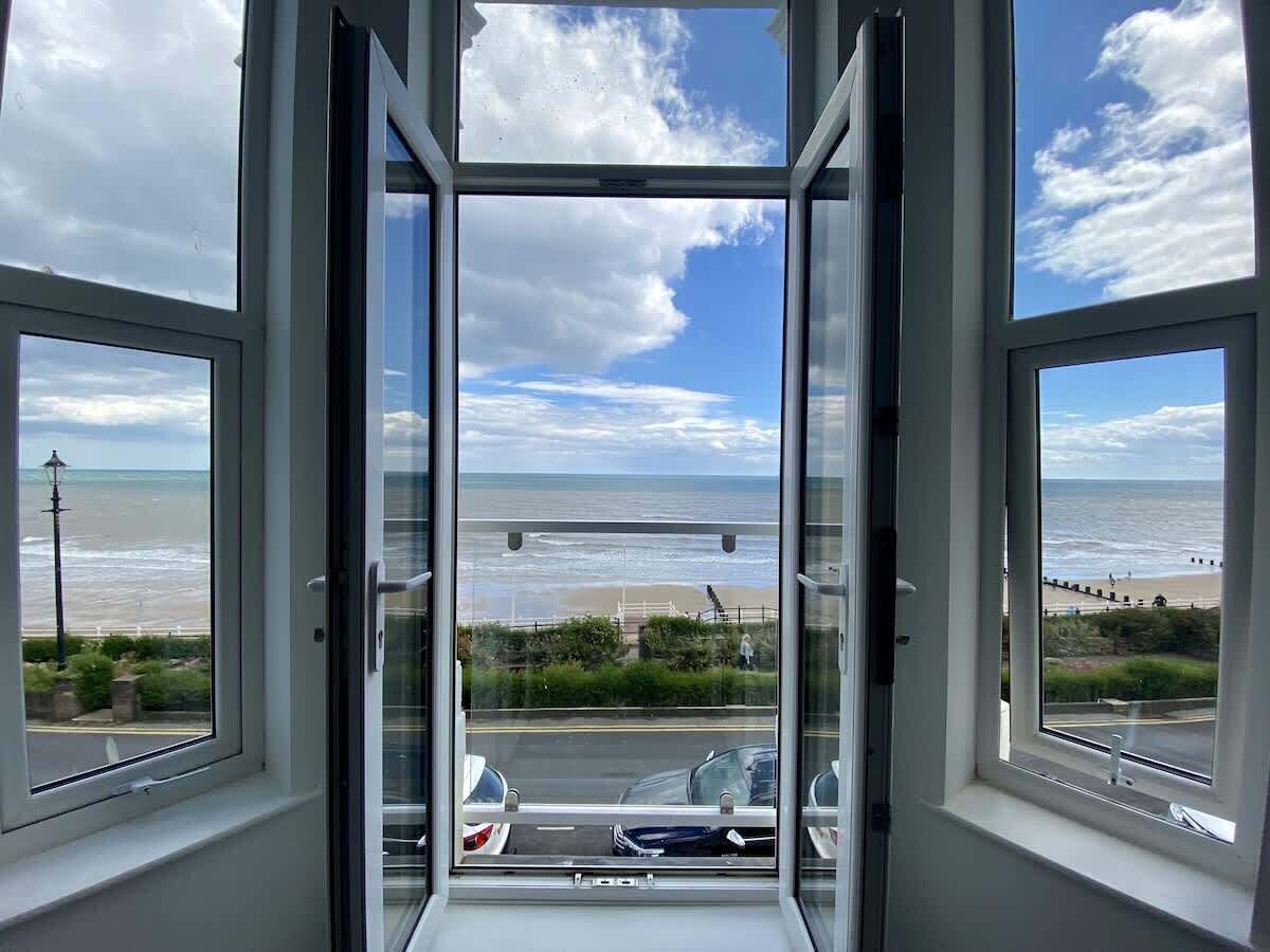 A room with a large window offering a view of the beach and the sea.