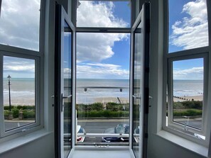 Una stanza con un'ampia finestra vista sulla spiaggia e sul mare.
